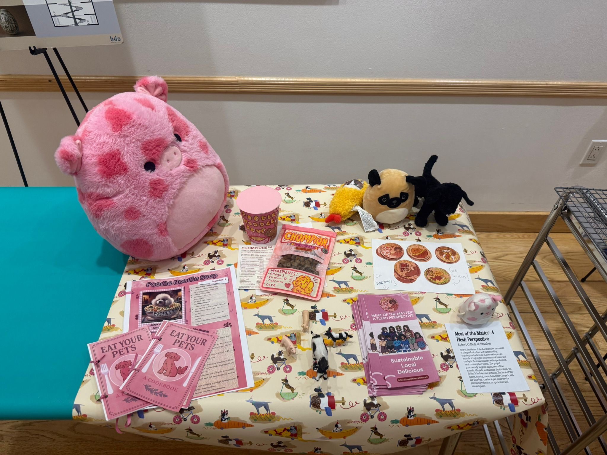 Exhibition table with satirical pet-meat products, cookbooks and plush animals
