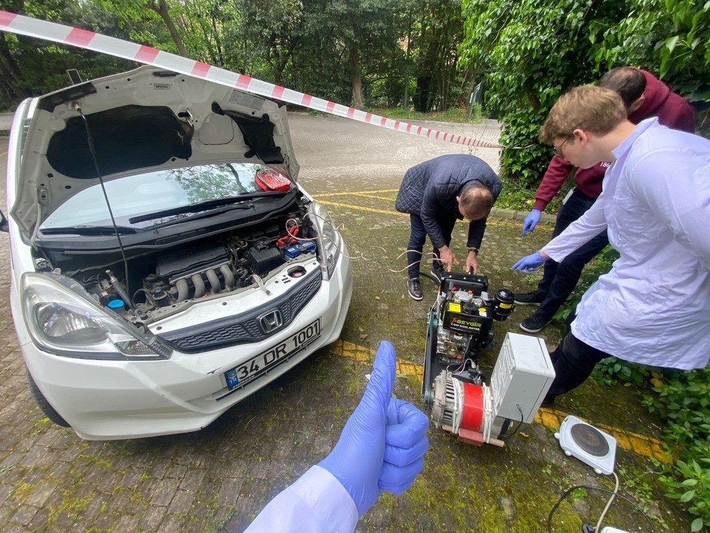 Outdoor test rig with a diesel engine and alternator beside a car