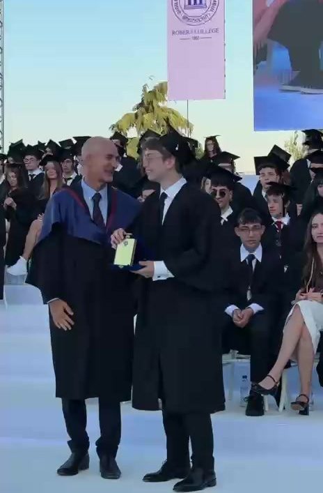 Receiving a graduation award plaque on stage in cap and gown