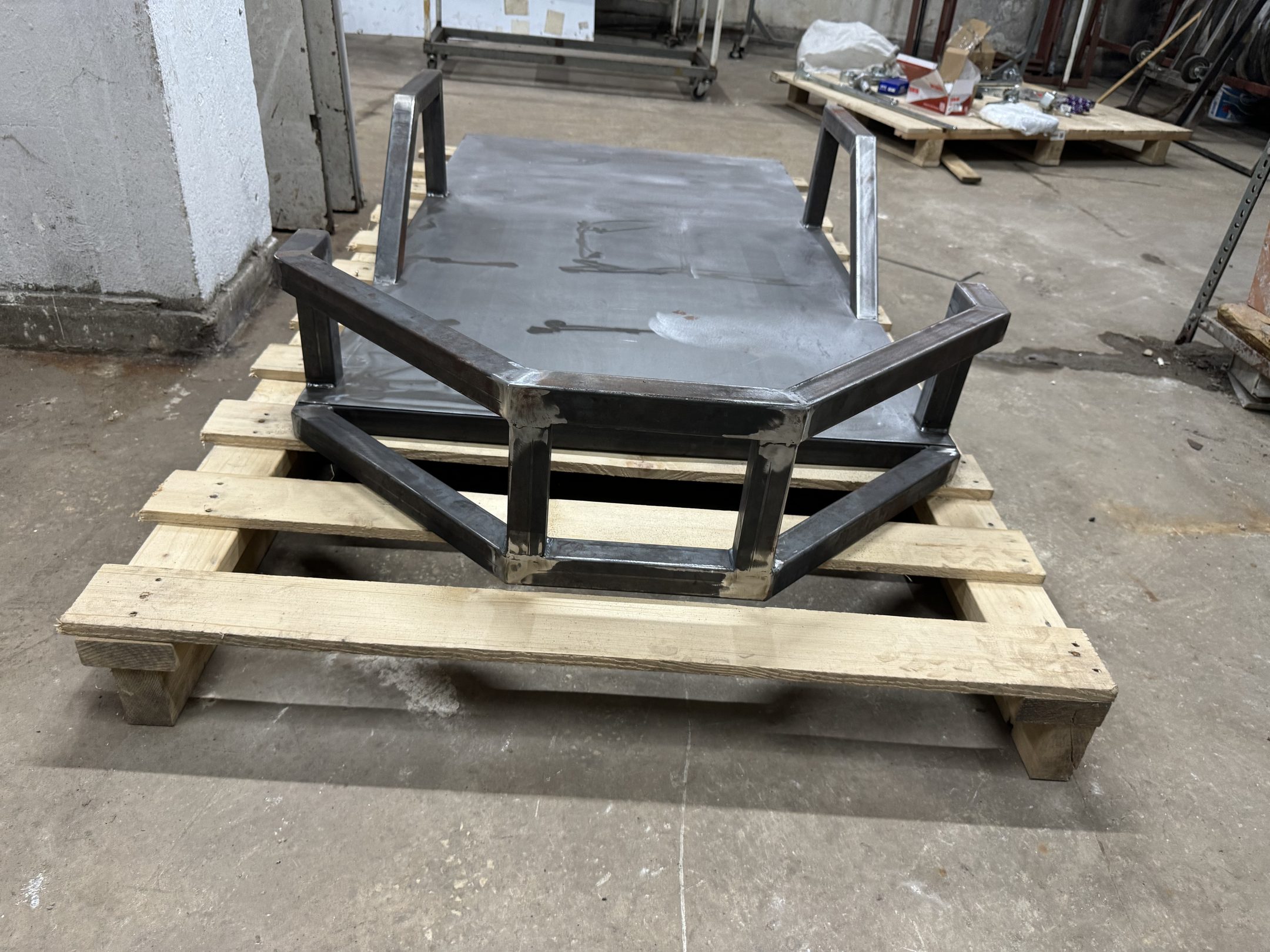 Bare welded steel chassis resting on a wooden pallet
