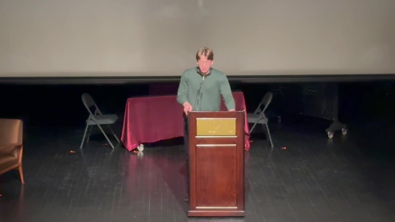 Speaking from a lectern on the auditorium stage